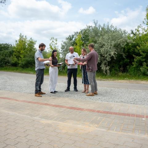 Grupka ludzi stoi na nowo wybudowanym chodniku