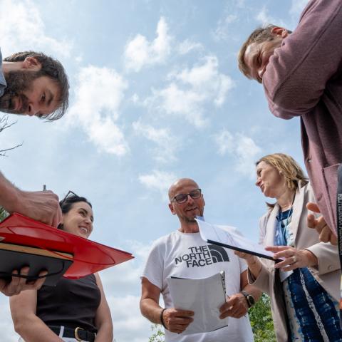 Grupka ludzi stoi na nowo wybudowanym chodniku, ujęcie z dołu