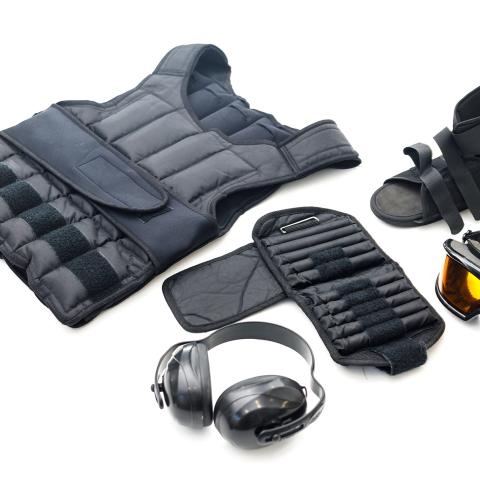 Poglądowe zdjęcie przedstawiające elementy wyposarzenia symulatota starości tytu GERT, to jest kamizelka z obciążnikami, słuchawki wygłuszające, gogle z żółtymi szkłami, usztywniacz stawów, obciażkik na kończyny górne.