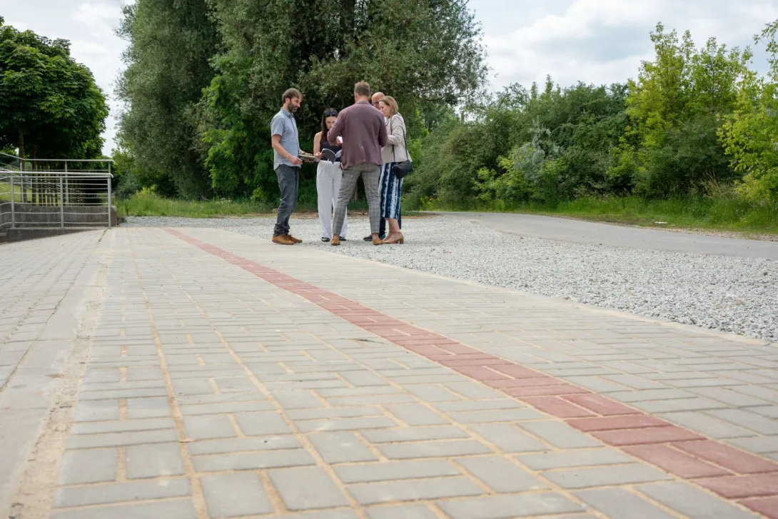 Grupka ludzi stoi na nowo wybudowanym chodniku